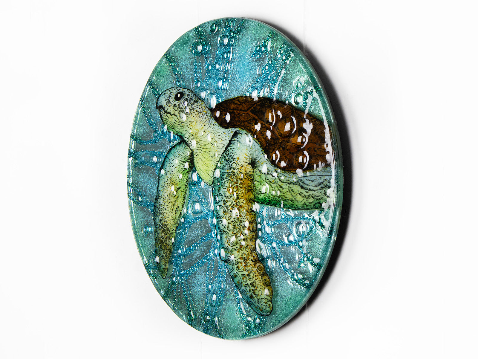 Fused glass round panel with hand-painted sea turtle and aqua bubbled background. An ocean inspired piece of wall art. 