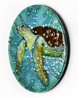 Fused glass round panel with hand-painted sea turtle and aqua bubbled background. An ocean inspired piece of wall art. 