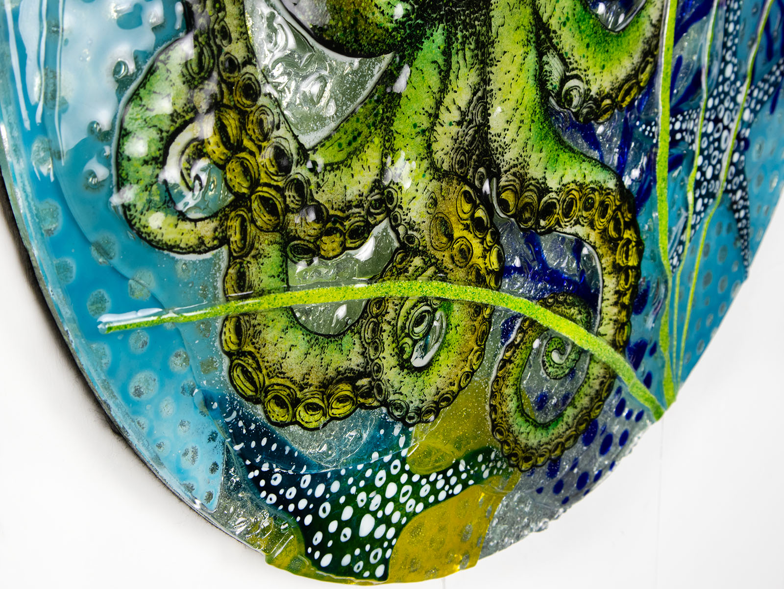 Fused glass round wall panel with a green octopus design, hand-painted with organic, textured detail. A ocean reef inspired piece of wall art. 
