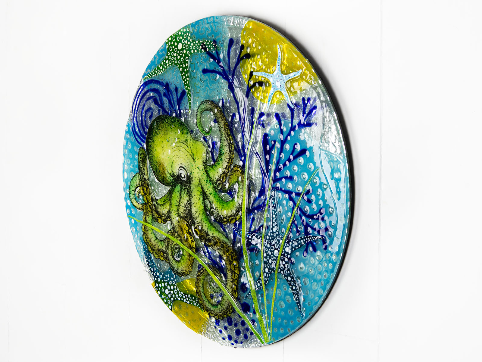 Fused glass round wall panel with a green octopus design, hand-painted with organic, textured detail. A ocean reef inspired piece of wall art. 