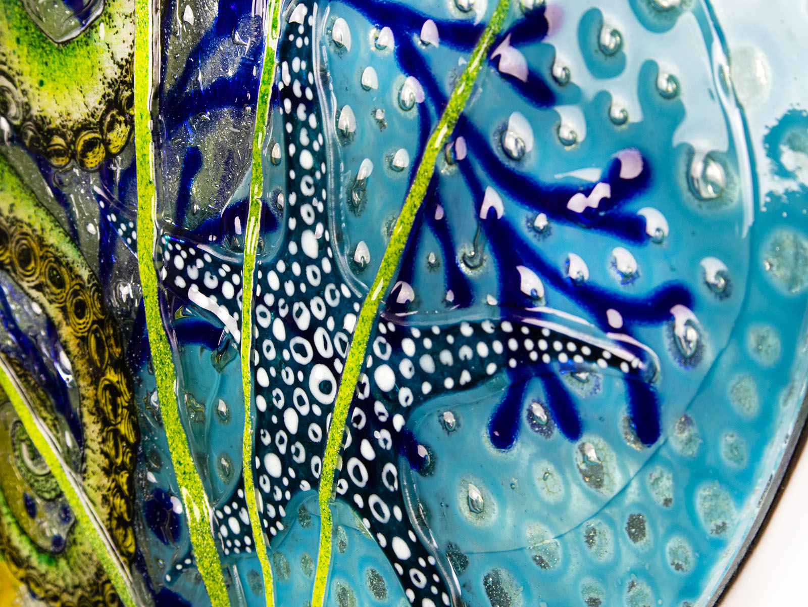 Close up of a blue starfish on a fused glass round panel in coastal colours.