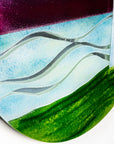 Wave details on a fused glass round panel inspired by a lighthouse on a coast-path with a sunset sky. 