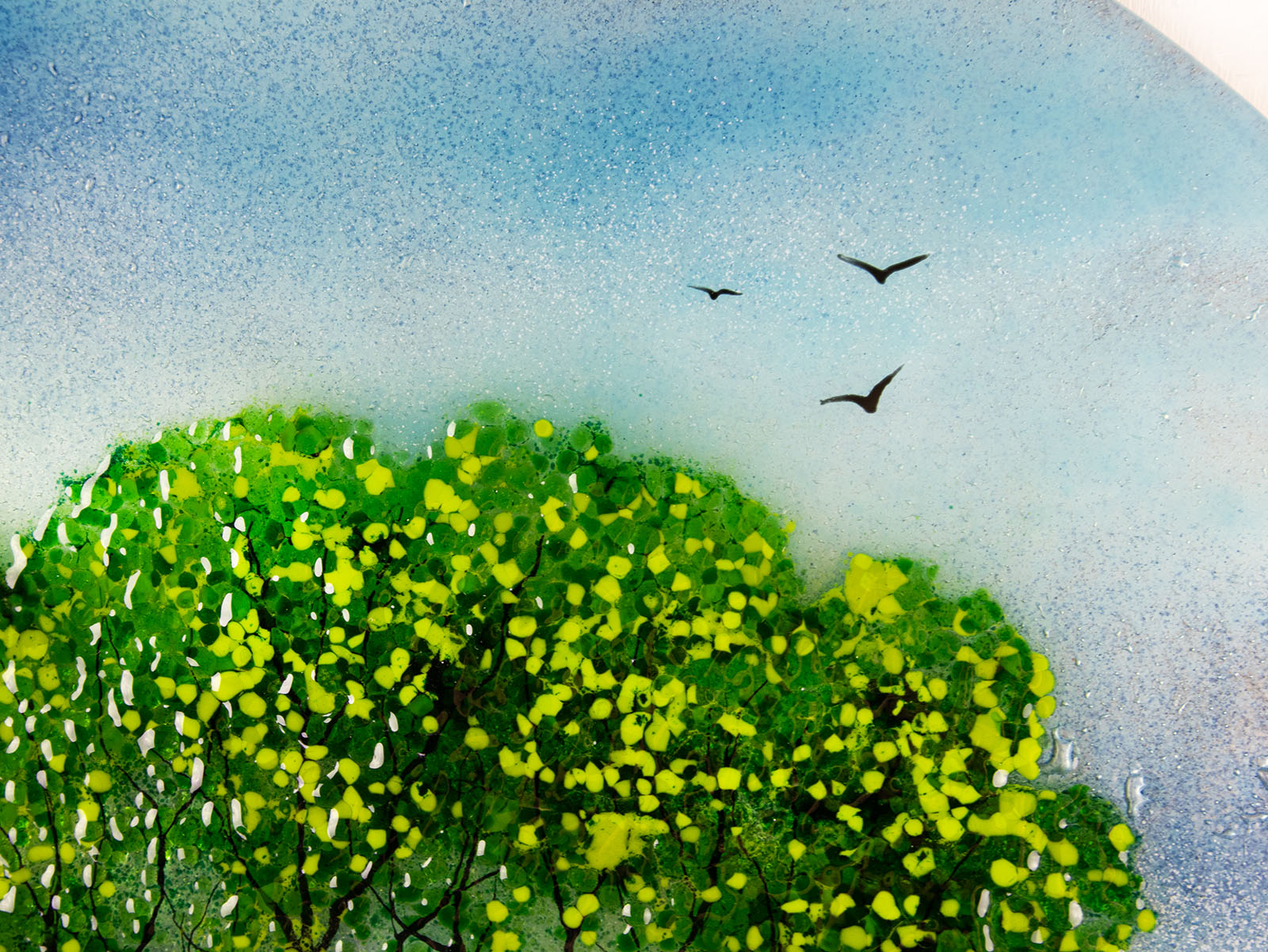 Details of fused glass round panel, inspired by the Nearly Home Trees in Devon, designed in bright summer greens. Panel includes hand-painted birds and texture.