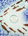 Close up of design on fused glass square dish, handmade in coastal blues, with copper fish. 