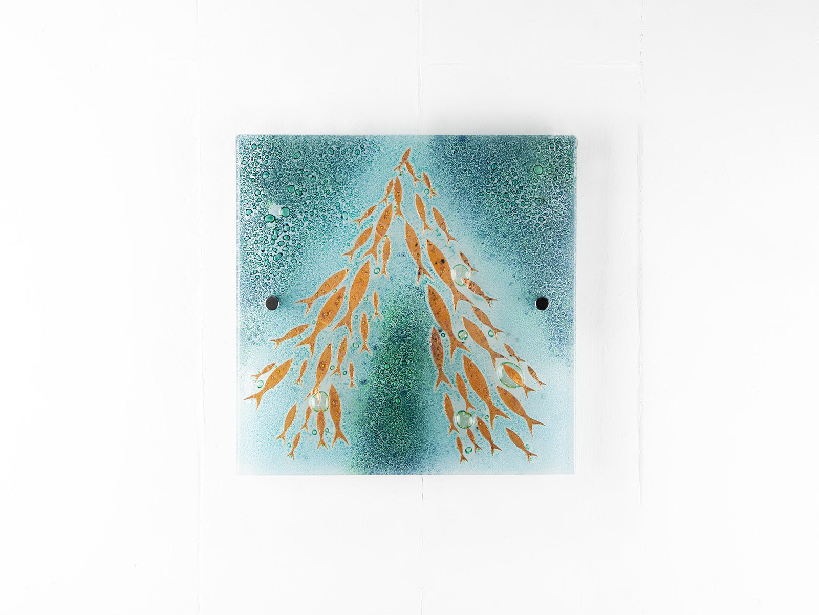 Fused glass square wall panel, featuring sea green colours and copper fish detailing. 