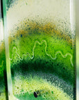 Close up of a fused glass triptych with emerald green colours in an organic, ocean inspired design. 