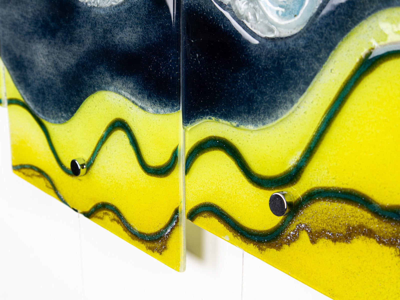 Details of a fused glass triptych with bright yellow wavy detailing, capturing a gorgeous ocean design. 