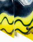 Details of a fused glass triptych with bright yellow wavy detailing, capturing a gorgeous ocean design. 