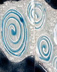 Details of a fused glass triptych with swirling detailing, capturing a gorgeous ocean design. 