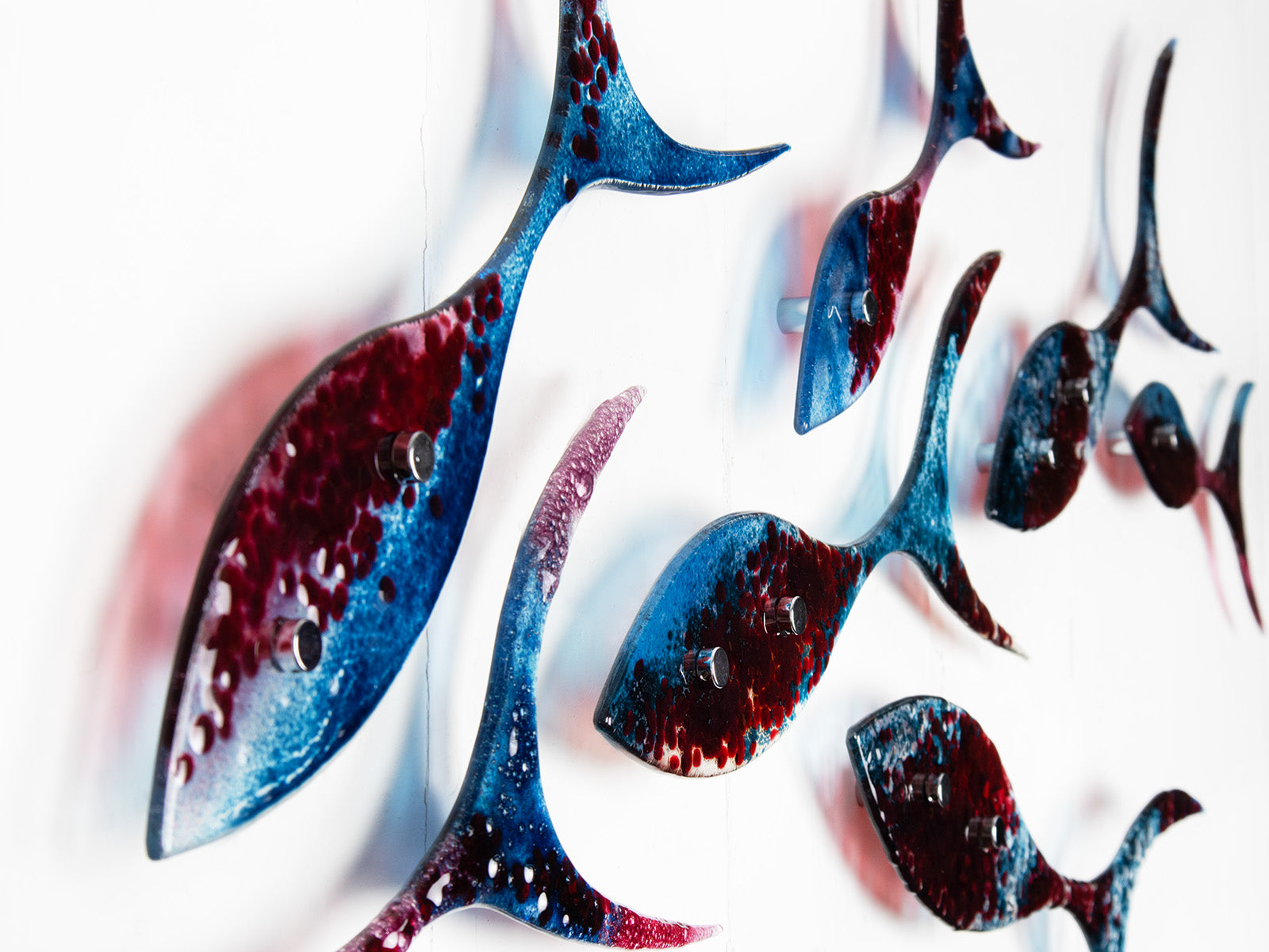 Detail of fused glass shoal of fish in a soft blue and textured burgundy colour-way.