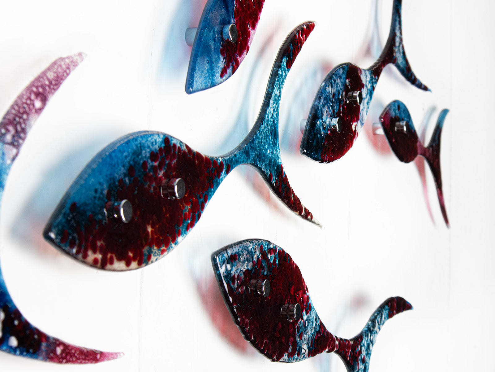 Close up of fused glass shoal of fish in a soft blue and textured burgundy colour-way.