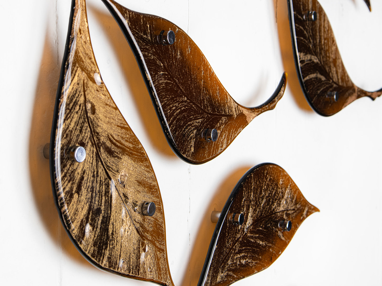 Close up of fused glass leaf wall art installation, designed in organic brown hues with shimmering gold detail. 