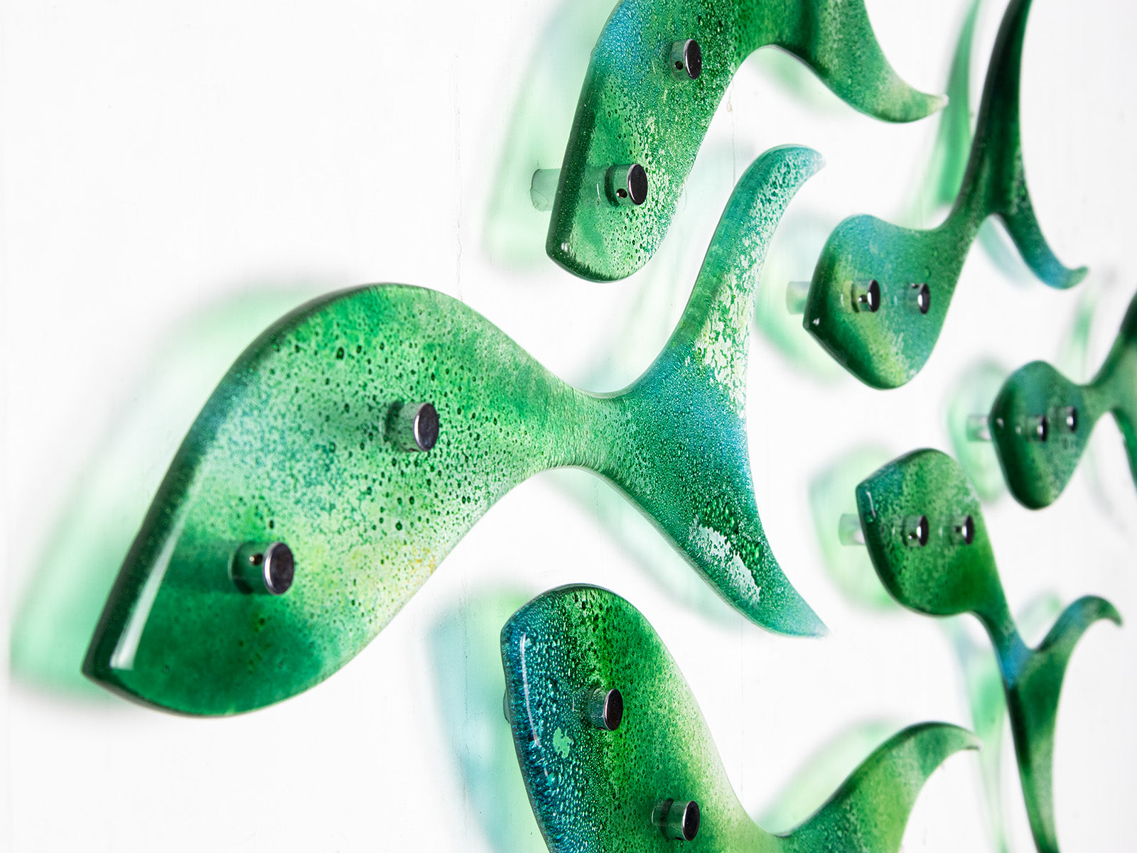 Close up of fused glass shoal of fish in a sea green and aqua colour-way. 