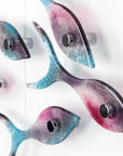 Close up of fused glass shoal of fish on a wall, handmade in bright pinks and coastal blues.