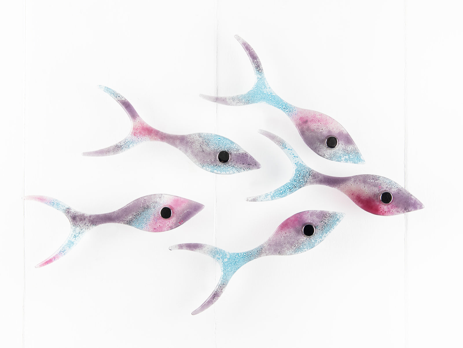 Fused glass shoal of fish on a wall, handmade in bright pinks and coastal blues.