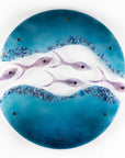 Fused glass wall art display with shoal of fish and coastal blue colours. 