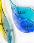 Close up of fused glass leaf wall art display in bright yellows and sky blues. 