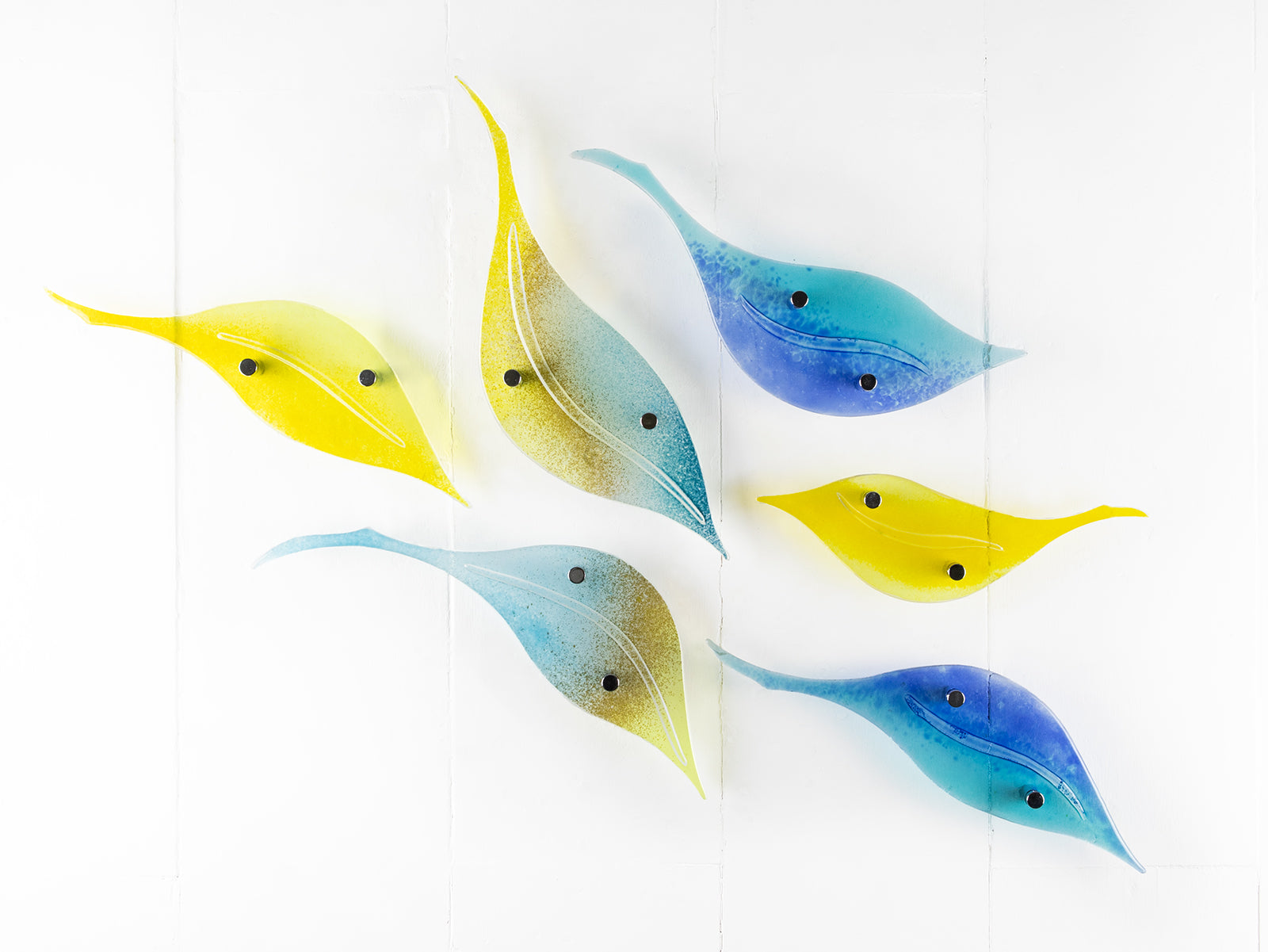 Fused glass leaf wall art display in bright yellows and sky blues. 