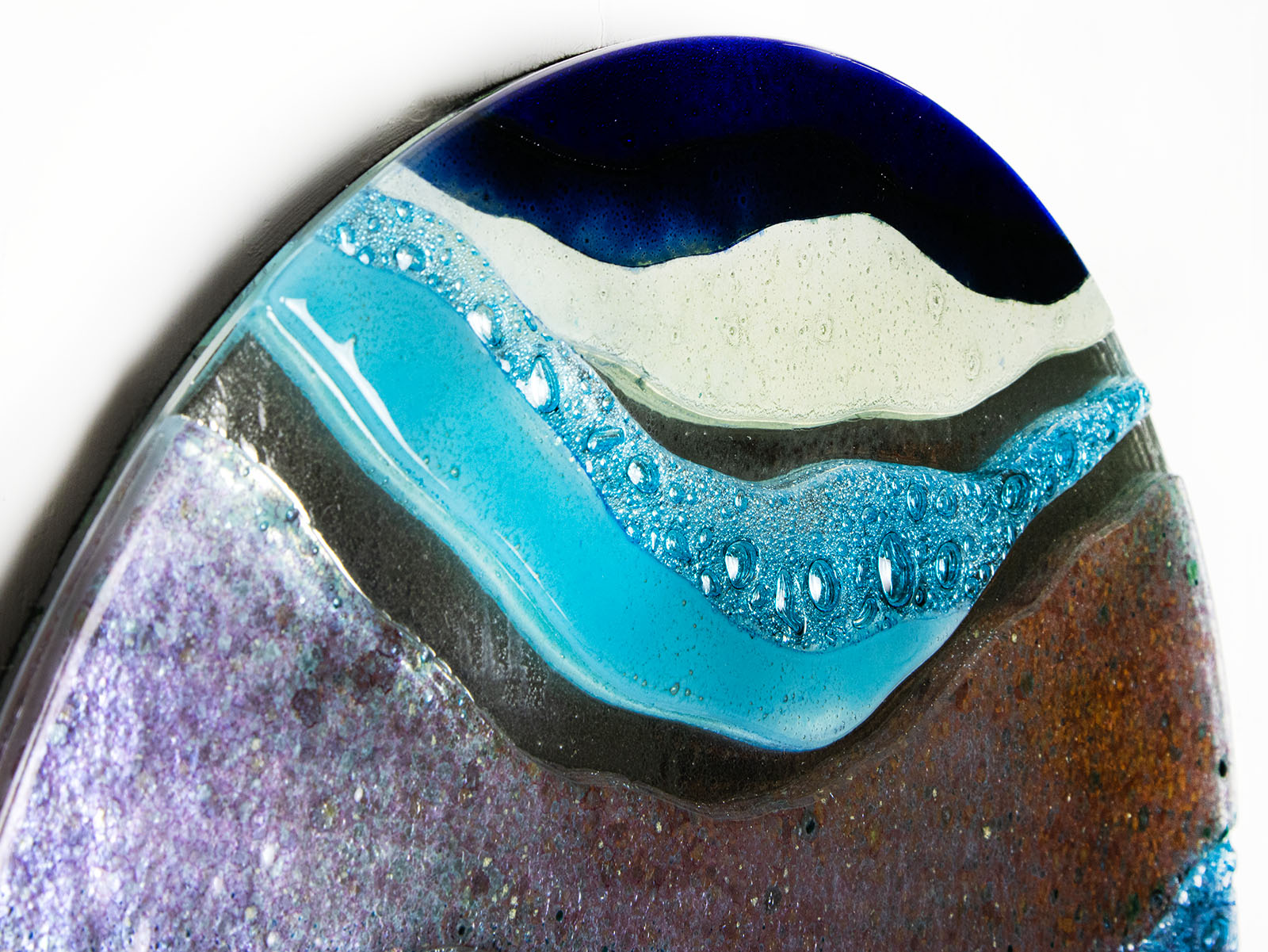 Wavy detail of abstract fused glass round panel, with gorgeous design in ocean purple colours and texture. 