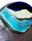 Wavy detail of abstract fused glass round panel, with gorgeous design in ocean purple colours and texture. 