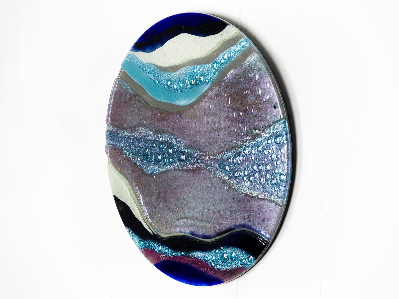 Abstract fused glass round panel, with wavy design in ocean purple colours and texture. 