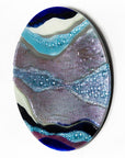 Abstract fused glass round panel, with wavy design in ocean purple colours and texture. 