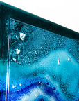 Close up of abstract and bright fused glass wall panel, inspired by the ocean with coastal colours and bubbled detailing. 
