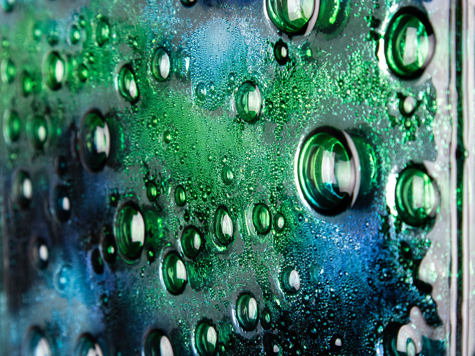 Close up of abstract and bright fused glass wall panel, inspired by the ocean, with coastal colours and bubbled detail. 