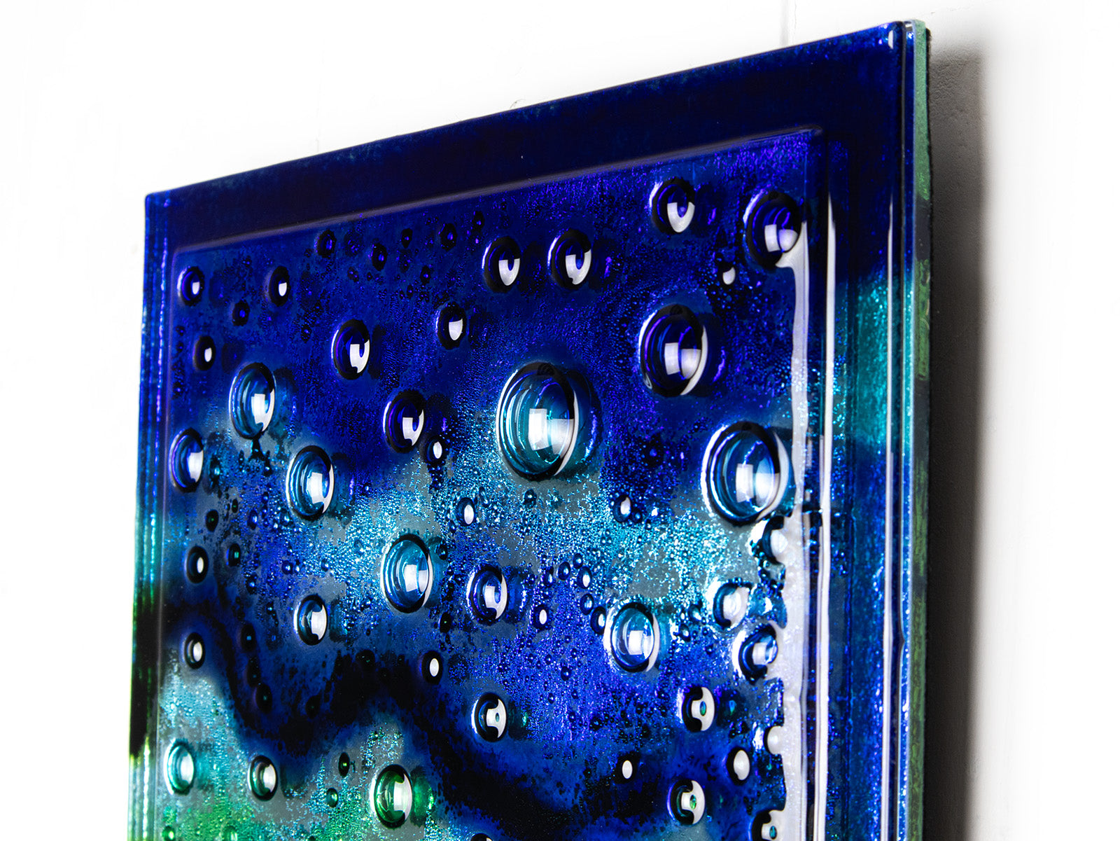 Bubbled detailing on abstract and bright fused glass wall panel, inspired by the ocean, with coastal colours.