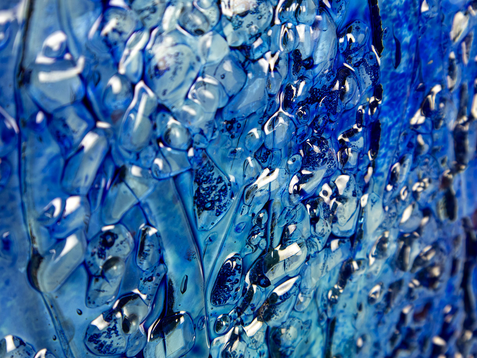 Close up of a fused glass ocean inspired wall panel with texture and bright blues.