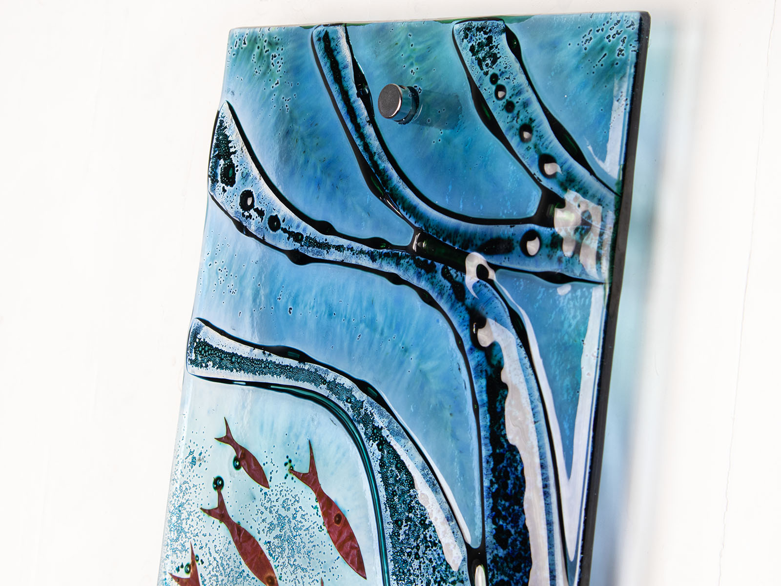 Close up of fused glass wall panel, with wavy detail and marine hues.