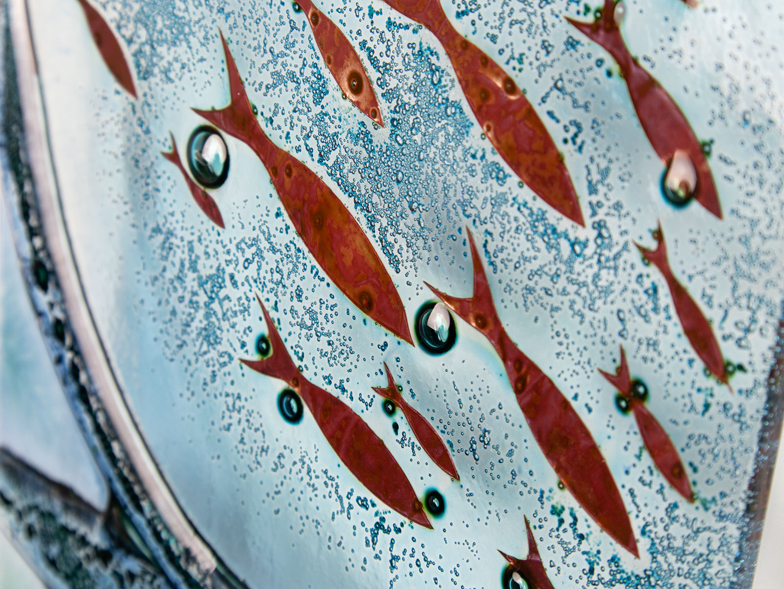 Copper fish detailing on a fused glass wall panel with blue colours. 
