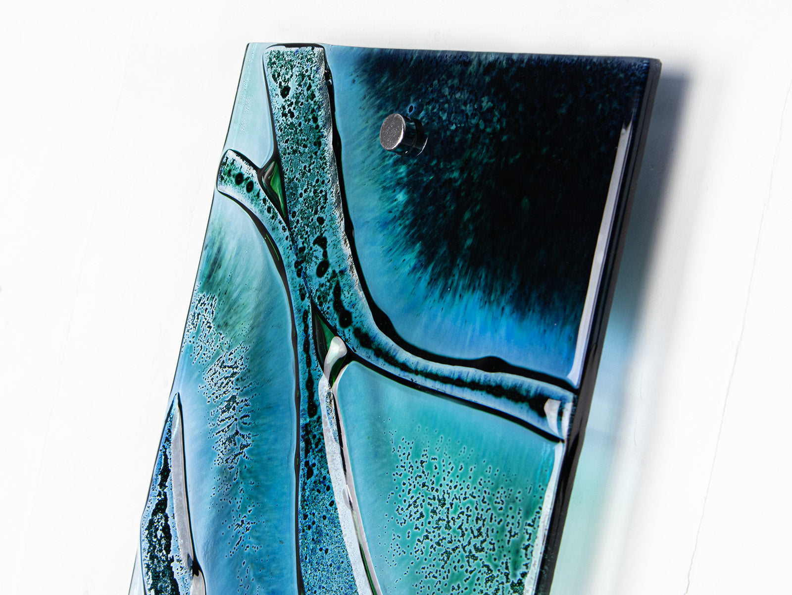 Close up of fused glass wall panel, crafted with marine blues and wavy detail. 