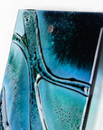 Close up of fused glass wall panel, crafted with marine blues and wavy detail. 