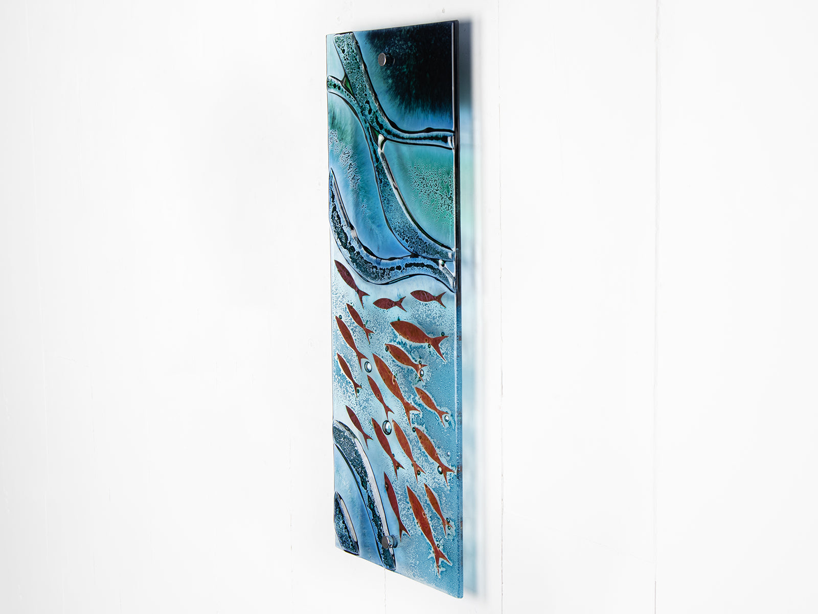 Fused glass wall panel featuring an ocean inspired design in marine blue hues and copper fish.