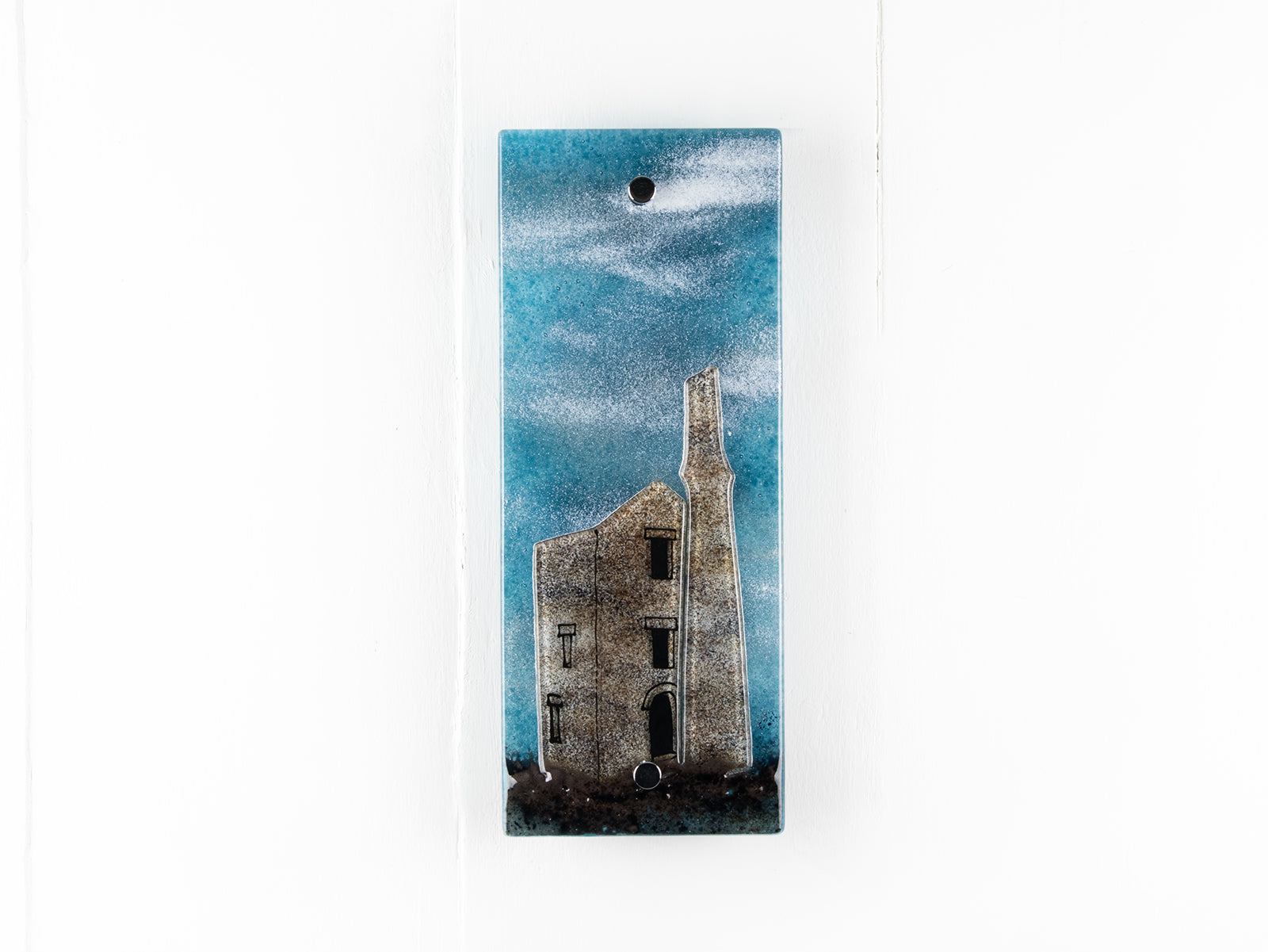 Small fused glass wall panel featuring a Cornish tin mine design, with a misty blue sky. 
