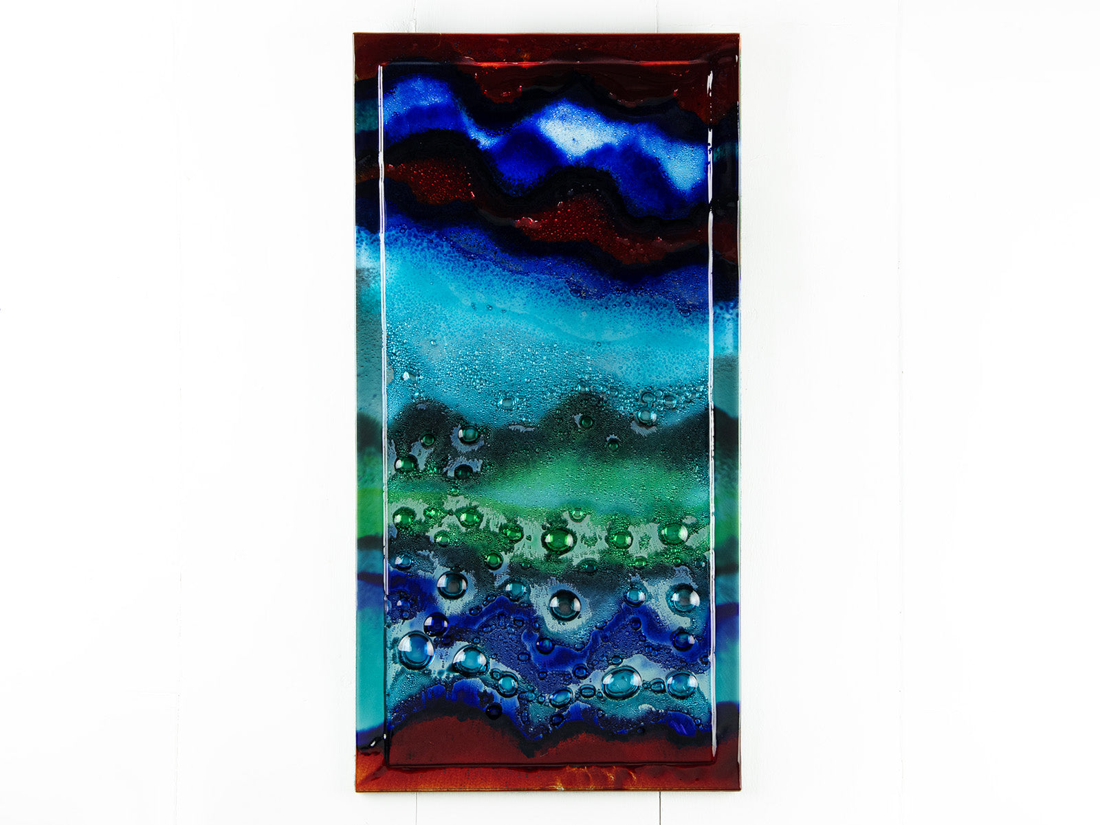 An abstract and bright fused glass wall panel, inspired by the atmosphere of the ocean, with coastal colours and bubbled detailing. 