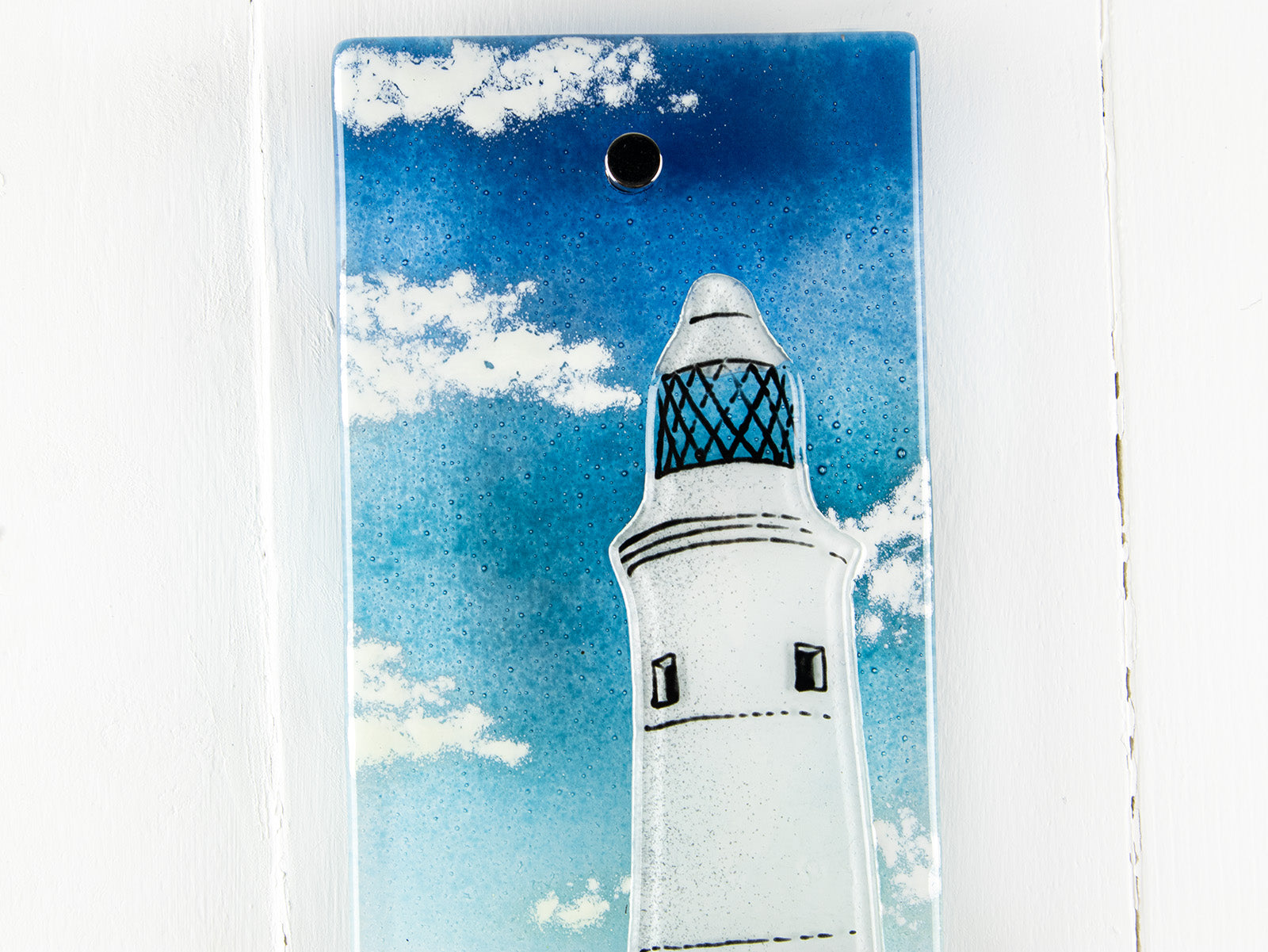 Close up of fused glass wall panel, made with a lighthouse design by the coast. Stunning coastal hues, a stunning hand-made piece of wall art. 