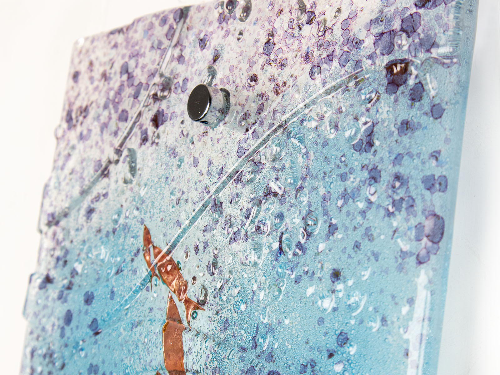 Details of fused glass wall panel in an ocean inspired design with copper fish and soft ocean colours. 