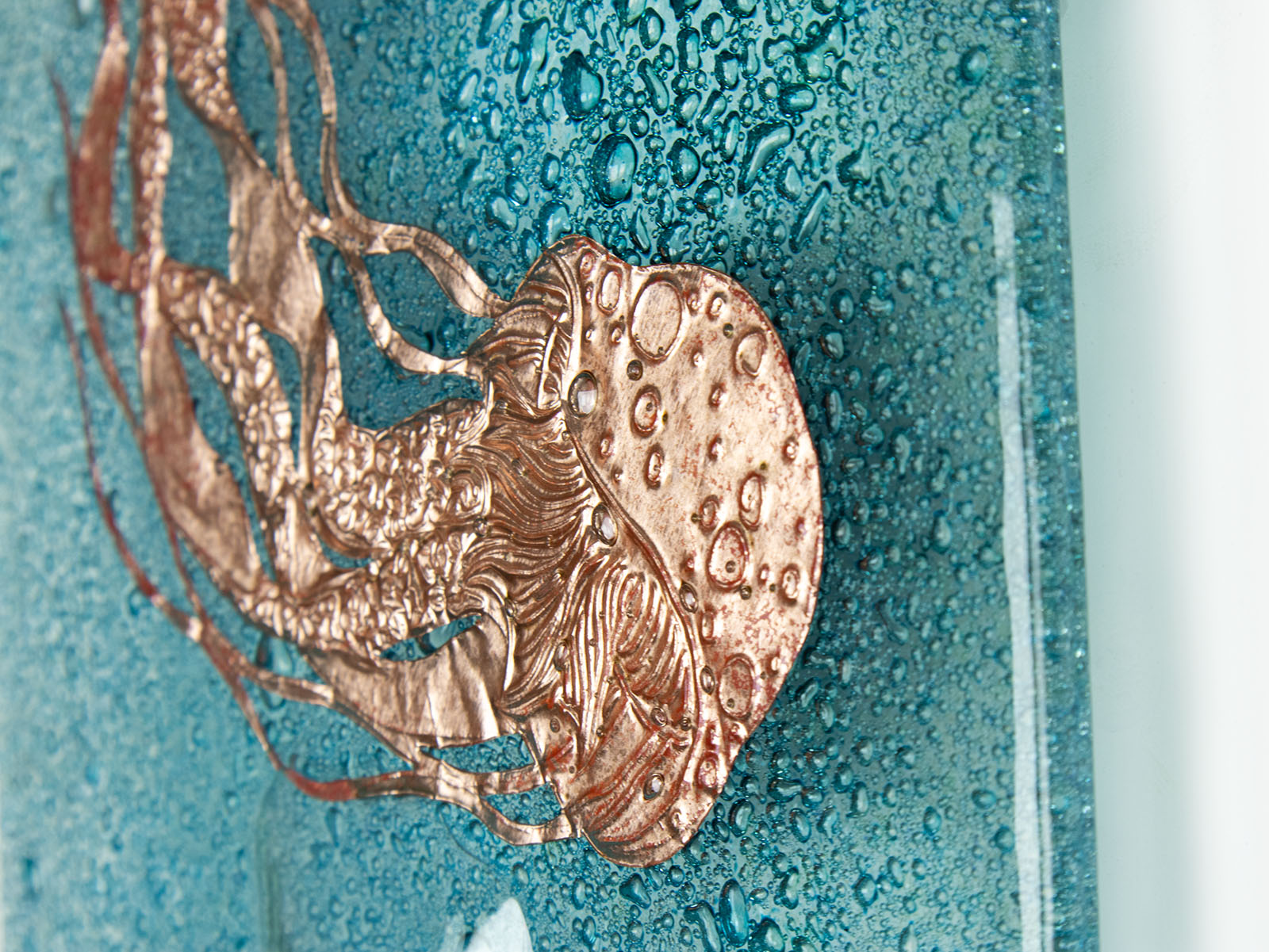 Details of hand-etched copper jellyfish on a fused glass wall panel, inspired by the coast. 