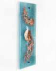 Fused glass wall panel featuring a hand-etched, copper jellyfish design on a aqua bubble blue background. 