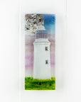 Small fused glass wall panel with a Cornish lighthouse and full moon design, with coastal hues and a blushed pink sky. 