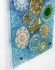 Fused glass wall panel, designed with organic textural detail and aqua, marine blues.
