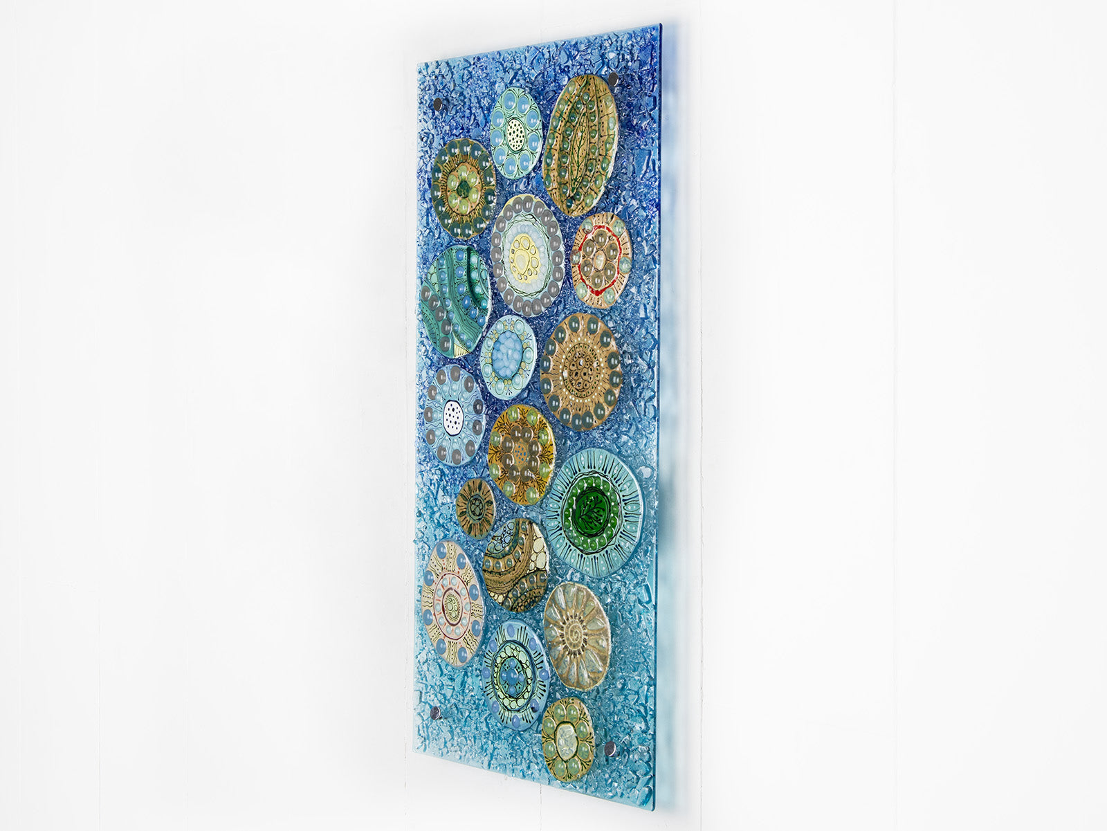 Side image of fused glass wall panel, designed with organic textural detail and aqua, marine blues.