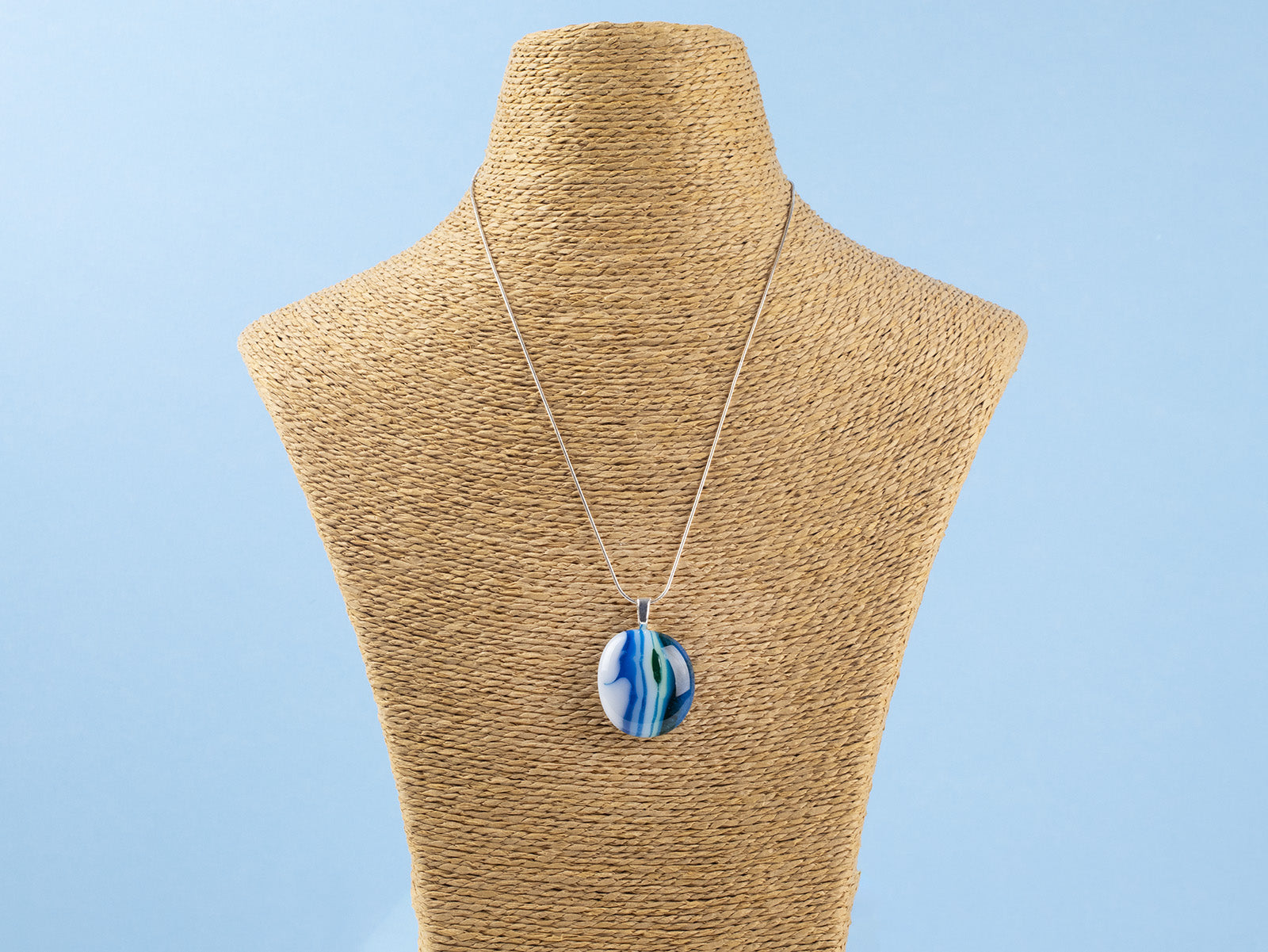 Fused glass pendant necklace, handmade in coastal blues, hung on a sterling silver chain. 
