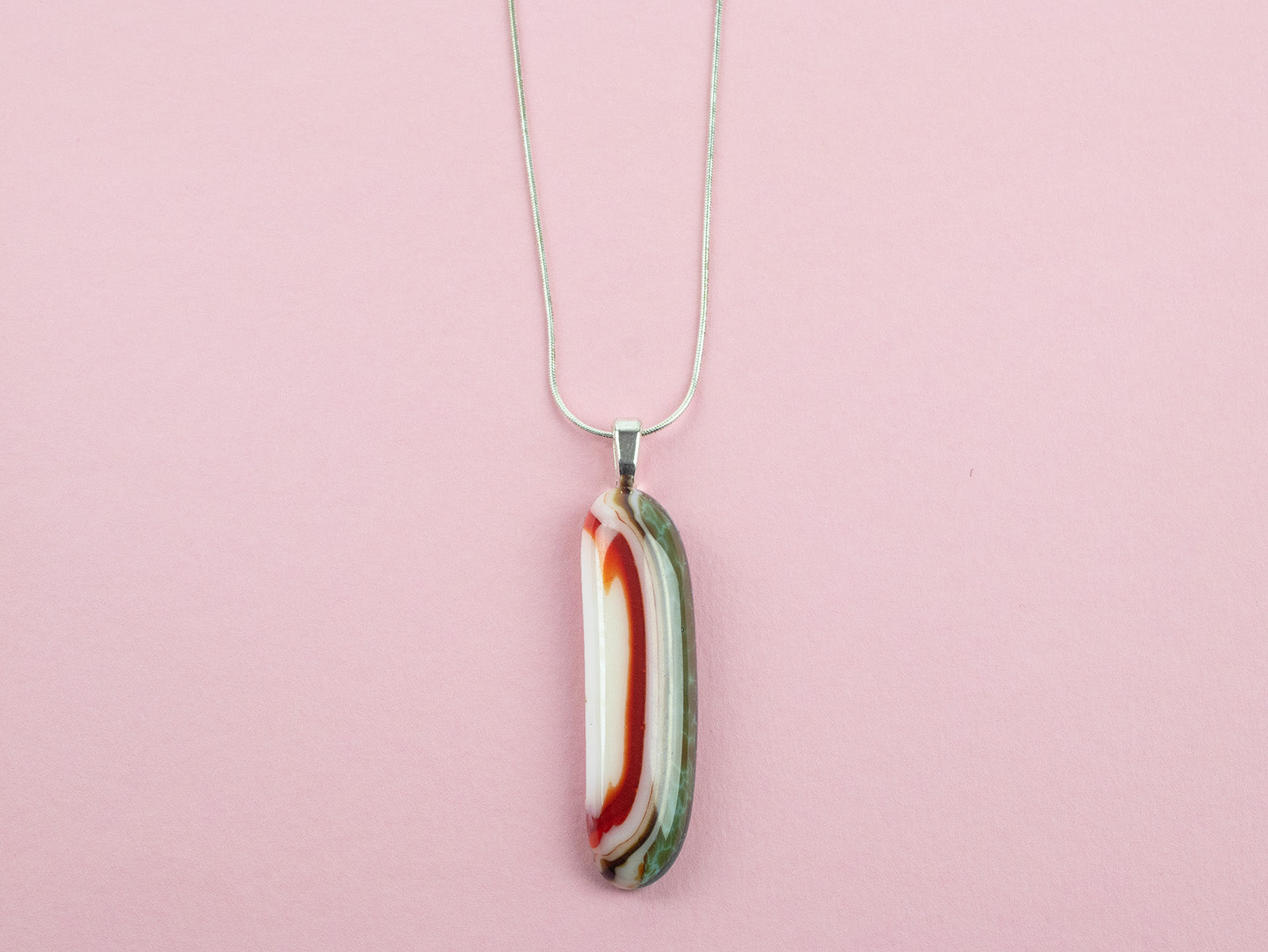 Close up of fused glass pendant necklace, handmade in sea greens and rose pinks, hung n sterling silver chain. 
