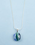 close up of fused glass necklace, handmade with ocean blues and hung on sterling silver chain.