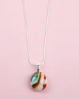 Close up of fused glass pendant necklace, handmade in sea greens and rose pinks, hung on sterling silver chain. 