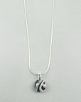 Close up of fused glass pendant necklace, handmade in soft coastal hues, hung on a sterling silver chain. 
