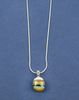 Close up of fused glass pendant necklace, handmade in soft coastal colours, hung on sterling silver chain. 